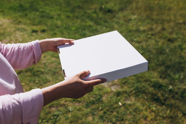 女人手里拿着一个披萨盒子，背景是自然。披萨外卖快。模拟。快餐横幅，夏日时光图片下载