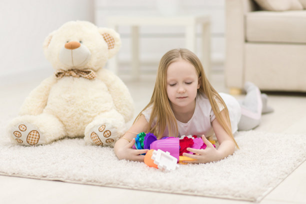 金发女孩躺在地板上的白色地毯上和玩具的照片。图片下载