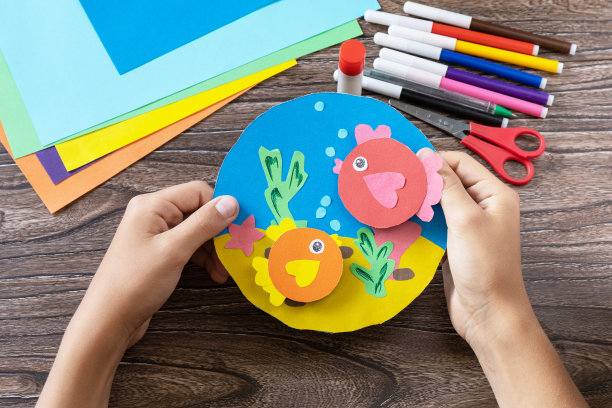 孩子捧着夏卡海卷着鱼。手工制作的。儿童创意项目，为儿童制作工艺品。图片下载