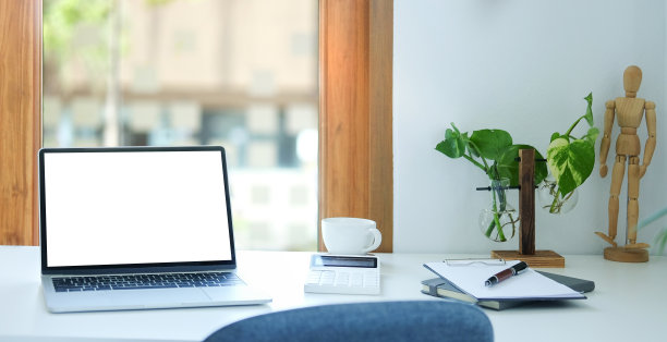 舒适的工作场所，笔记本电脑，咖啡杯，笔记本和室内植物在白色的桌子上。图片下载