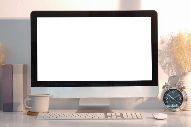 现代化的办公场所，白色的桌子上放着电脑、书籍、闹钟和咖啡杯。图片下载