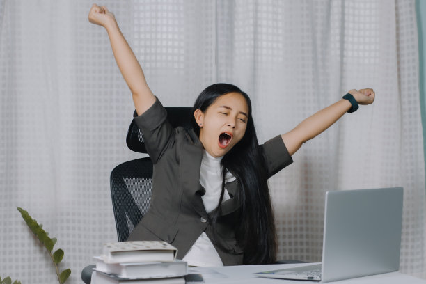 亚洲女性在办公室用笔记本电脑工作时打哈欠。图片下载