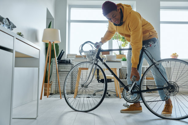 自信的年轻多种族男子检查他的自行车和微笑图片下载