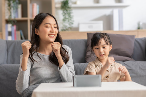 幸福的亚洲母女看着智能手机上的音乐视频app一起唱歌跳舞。快乐的妈妈和孩子录制视频，分享在社交媒体流媒体应用程序有乐趣图片下载