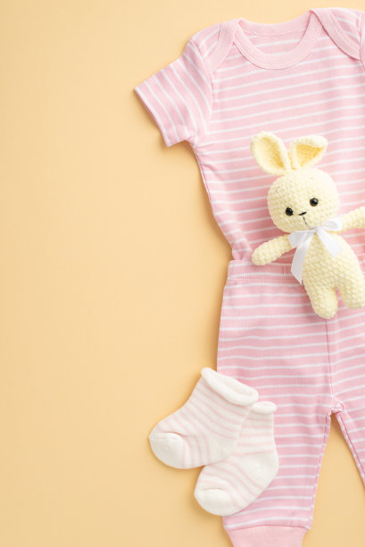 婴儿的概念。俯视图垂直照片的粉红色衬衫内裤袜子和针织兔子玩具在孤立的粉彩米色背景图片下载