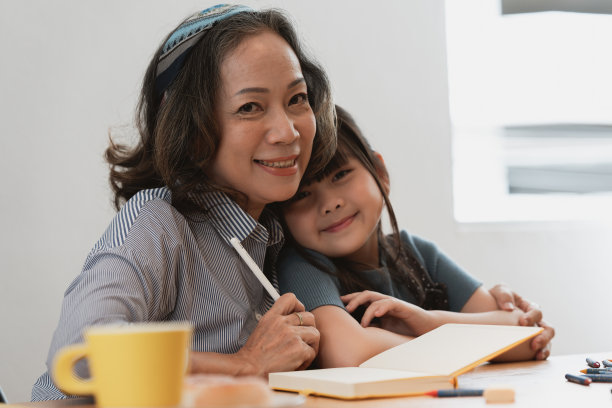 快乐的时刻孙女给拥抱，而亚洲资深商业女性在家里工作。家庭的概念。图片下载