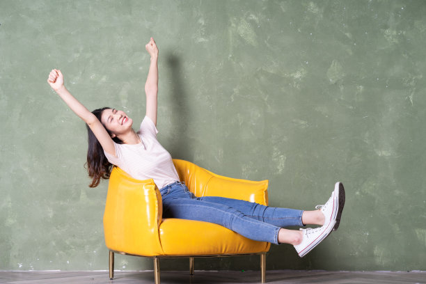 年轻漂亮的亚洲女人坐在黄色扶手椅上的形象图片下载