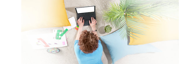 在家创造性工作的横幅。女孩躺在她公寓的地板上，带着笔记本电脑。在家用笔记本电脑办公的女性。从以上观点。网上学习、教育、购物、工作理念图片下载