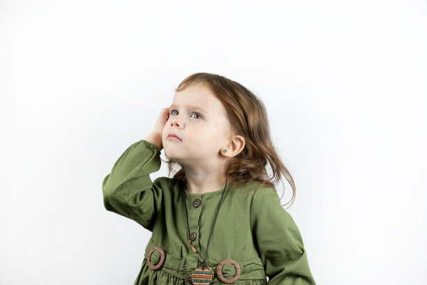 一个红头发的小孩在思考，他抬起头，把手放在头上。孤立的照片沉思的女孩在白色背景图片下载