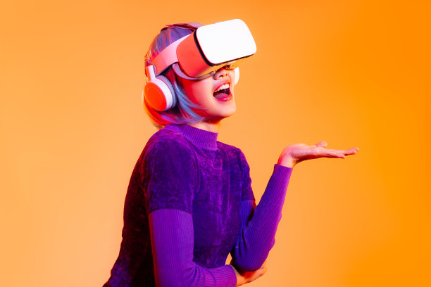 元宇宙概念，年轻的亚洲女子在紫色运动衫赛博朋克发型戴白色vr头显手呈现玩触摸观看在橙色屏幕背景。图片下载