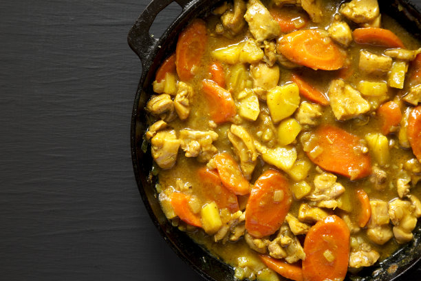 自制的日式咖喱鸡放在黑色背景的铸铁锅里，俯视图。平躺，在头顶上，从上面。空间的文本。图片下载