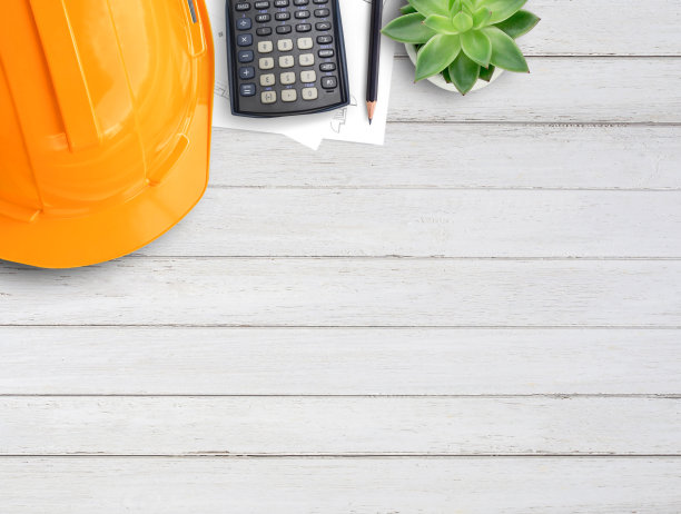 橙色安全帽或安全帽，咖啡，计算器和木制桌子背景上的图纸。图片下载