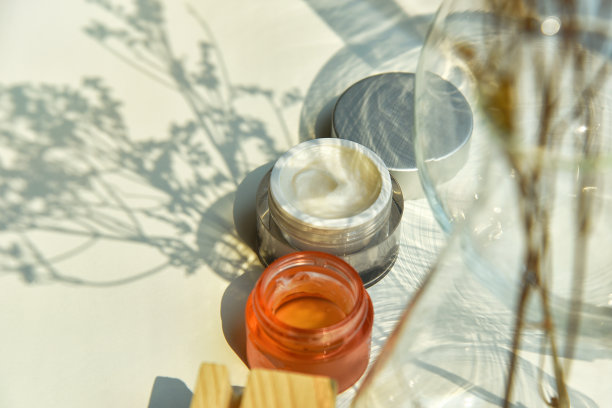 化妆品瓶身容器放在阳光和树叶的植物阴影背景下，护肤面霜，具有温暖心情和色调的美容产品。图片下载