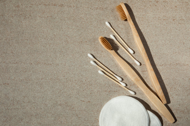 两把木制牙刷，棉垫和木棍放在浅色的背景上图片下载