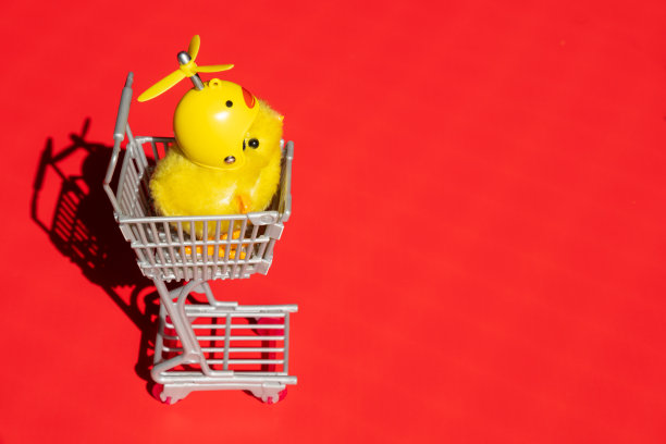 购物车里可爱的小女孩独自站在红色的背景上。图片下载