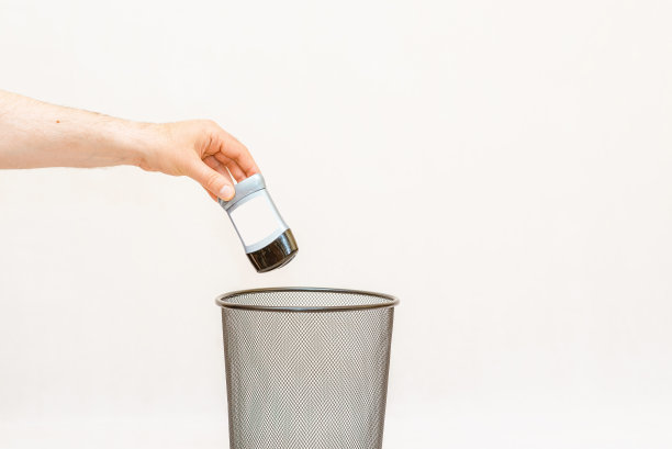 腋下止汗剂扔进垃圾桶，易拉罐处理回收。白色，灰色背景，选择性聚焦，复制空间。图片下载