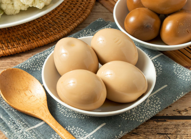 4金鸡蛋在一个白色的碗里，木勺孤立在垫子上俯瞰图片下载