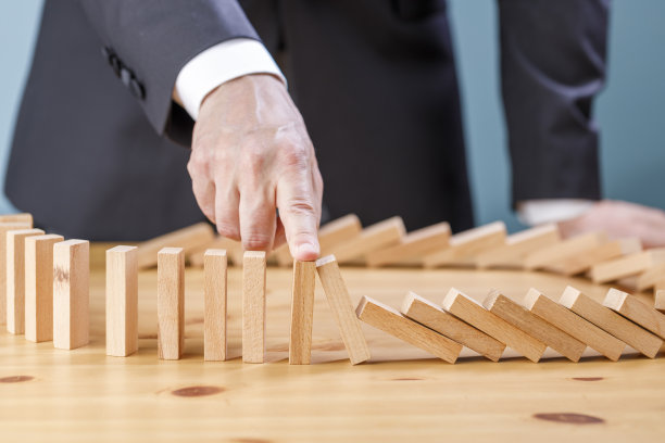 商人用风险观念阻止木块在多米诺骨牌上倒下图片下载