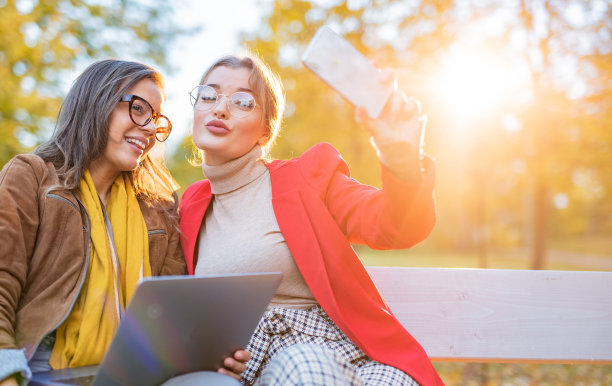 两个女学生在公园里用手机自拍图片下载