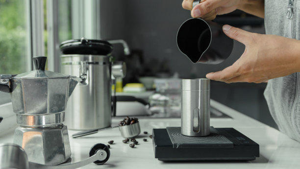 用手将煮好的咖啡粉倒入装有意式浓缩咖啡的器具工具的杯子中冲泡意大利摩卡壶，咖啡在厨房家中。准备喝图片下载
