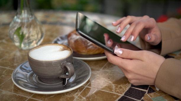 年轻的女商人坐在咖啡馆里，在平板电脑上写短信。图片下载