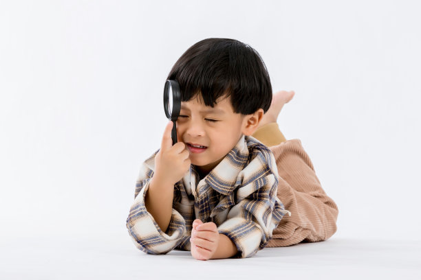 孩子拿着放大镜在白底。演播室里拿着放大镜的男孩。图片下载