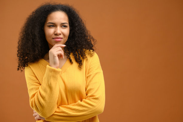 聪明体贴的女人托着下巴思考着想法，做着艰难的决定，一脸不确定的怀疑。室内工作室拍摄孤立的棕色图片下载