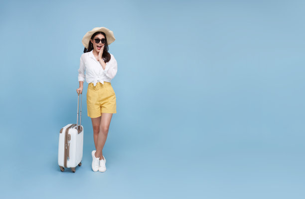 惊讶的年轻亚洲旅游妇女拿着行李去旅行假期孤立的蓝色背景。本空间图片下载