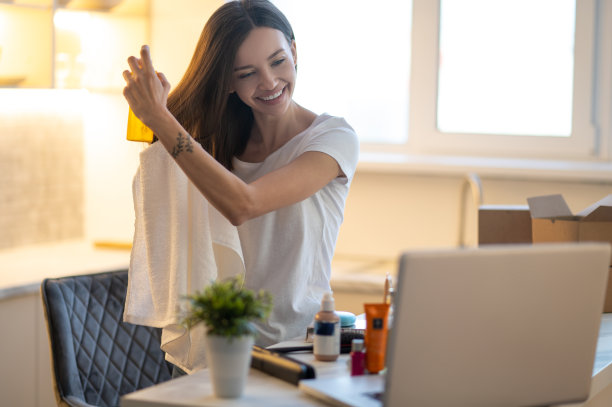 在笔记本电脑前往头发上喷角蛋白的女人图片下载