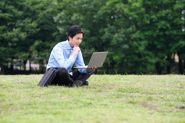 商人坐在草坪上使用笔记本电脑图片下载