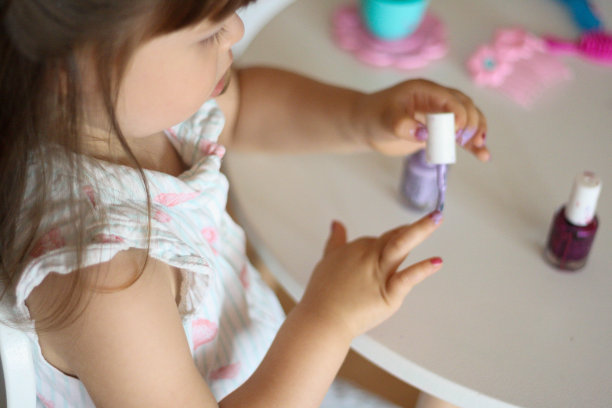 这个小女孩正在用儿童的指甲油给指甲上色。图片下载