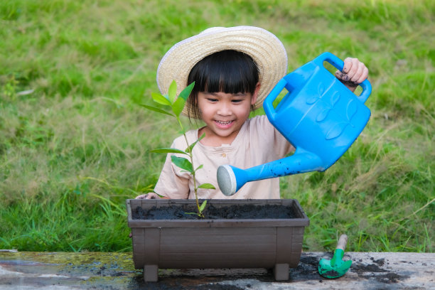 小女孩戴着帽子在花园里帮助她的妈妈，一个小园丁。可爱的女孩在花盆里种花出售。家庭小商业图片下载