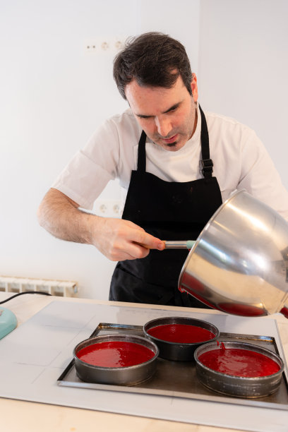 一名面包师在家里做一个红丝绒蛋糕，在放入烤箱之前先把蛋糕放入模具中，在家工作图片下载