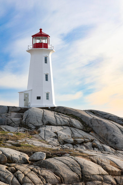 灯塔坐落在岩石上，天空中有云图片下载