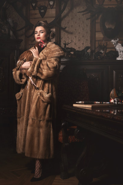 穿着裘皮大衣的美女抱着母鸡。动物权利的概念。图片下载