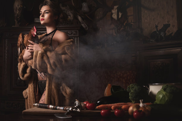 穿着裘皮大衣的美女抱着母鸡。动物权利的概念。图片下载