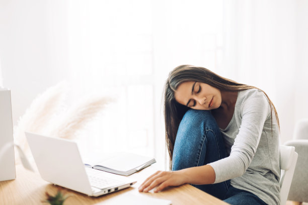 一个女学生闭着眼睛休息，头靠在膝盖上，准备上课或考试图片下载