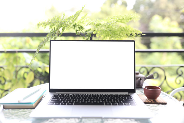 笔记本电脑正面视图和陶杯与笔记本在白色玻璃桌子户外图片下载