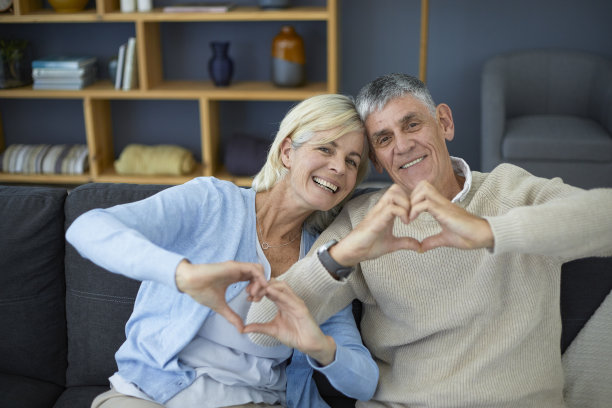可爱的老夫妇用他们的手做心形的手势图片下载