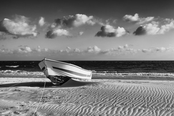 在西班牙安达卢西亚博洛尼亚的沙滩上，一艘孤独的木船靠近沙丘。图片下载