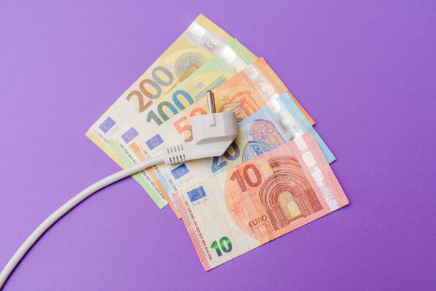 电插头，欧元纸币钞票。紫色在室内背景。电力成本增加对所有居民和企业用户，昂贵的能源账单和电价上涨的概念。图片下载