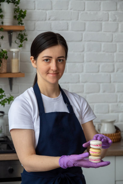 手里拿着马卡龙的糕点师肖像。有选择性的重点。关于甜点、食物的网站照片。图片下载