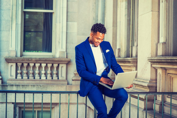 一个年轻人在纽约办公大楼外用笔记本电脑工作图片下载