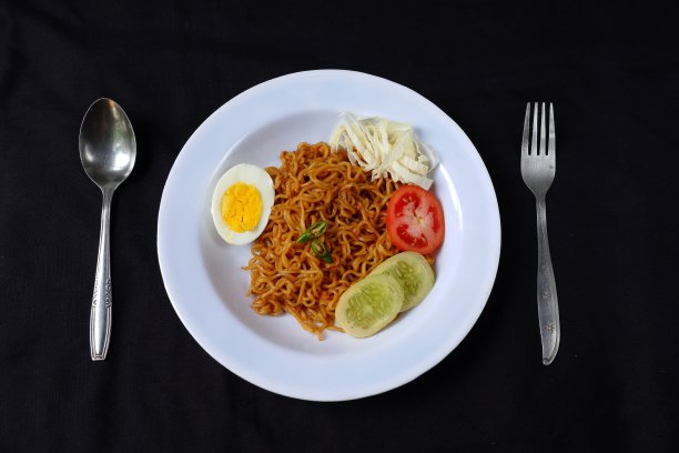 煎方便面与鸡蛋和蔬菜分离在黑色的背景图片下载