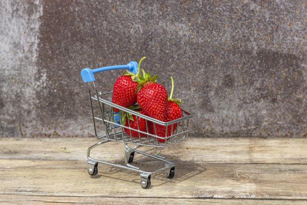成熟的草莓放在超市手推车上，背景是木制的图片下载