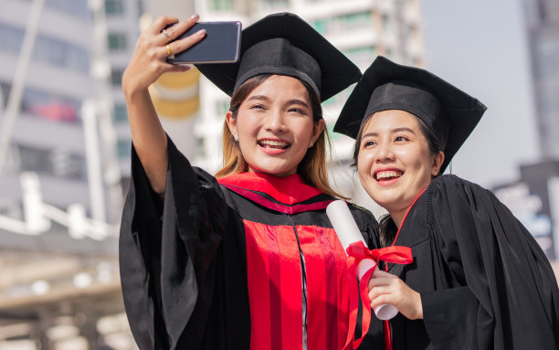 两名本科毕业的亚洲女大学生站在户外用手机自拍。教育科技理念。图片下载