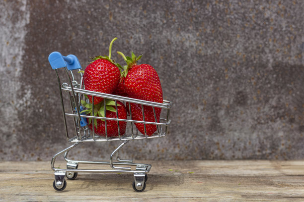 成熟的草莓放在超市手推车上，背景是木制的图片下载