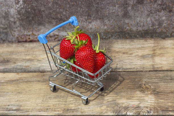 成熟的草莓放在超市手推车上，背景是木制的图片下载