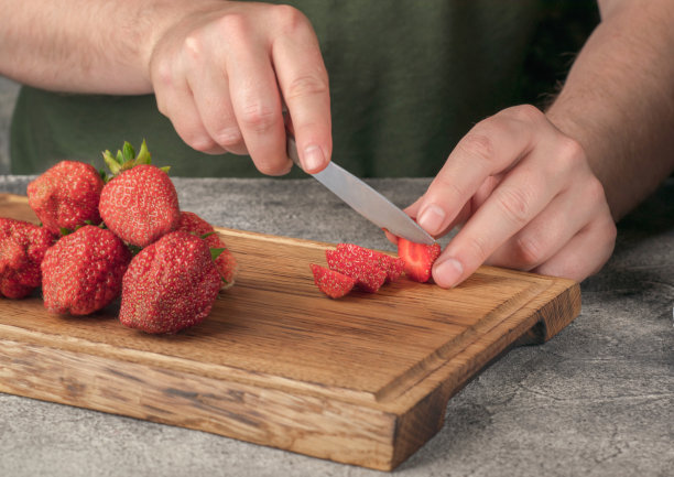 切草莓的过程手握着一把在木板上切草莓的刀。图片下载