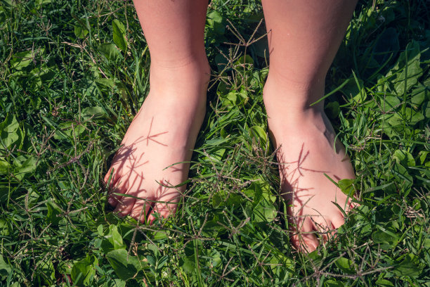 孩子的脚赤脚踩在绿色的草地上图片下载